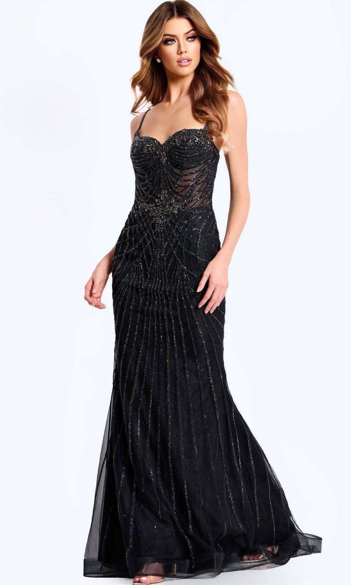 A woman wearing the Jovani 49117 long prom dress, featuring a fitted black design with thin straps, sheer panels, and intricate beaded details, stands against a plain light background.